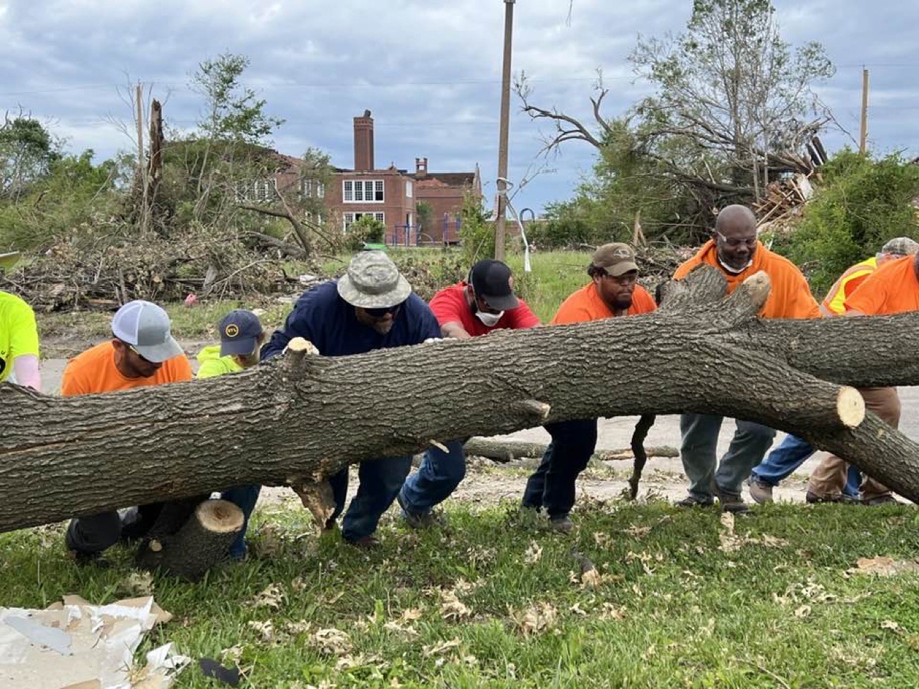 Greater St. Louis EWMC members lifting a fallen tree together during storm cleanup